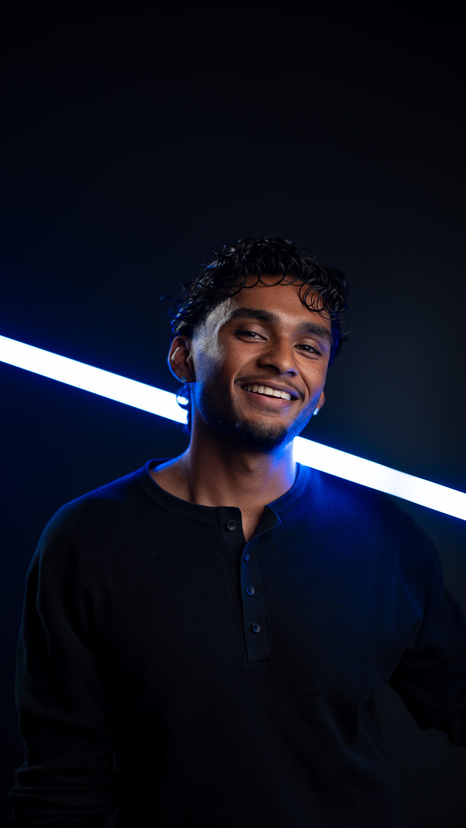 Rojith Ragavan, Head of Social und Co-Founder der Haldelain GmbH, im Studio mit blauer Lichtlinie